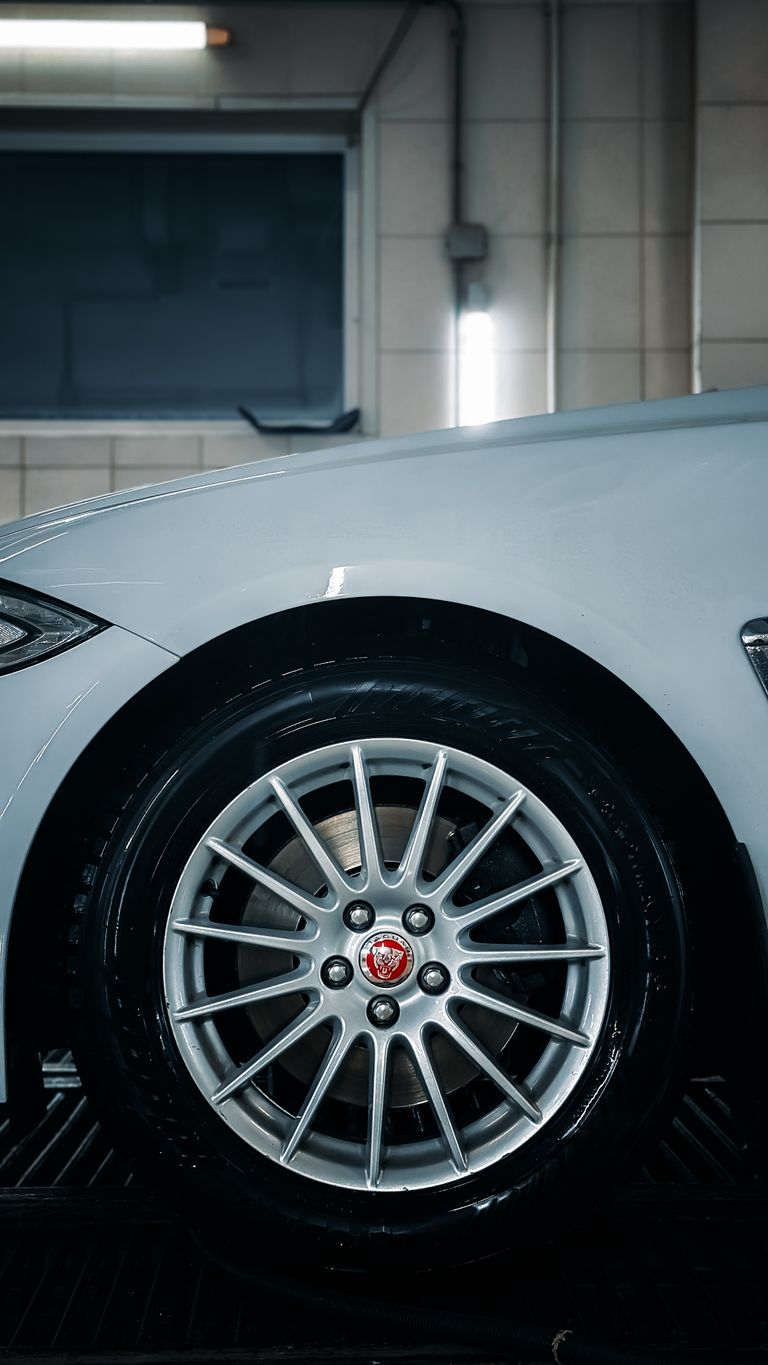 Close-up of a silver car wheel in a clean indoor garage setting, showcasing modern design.