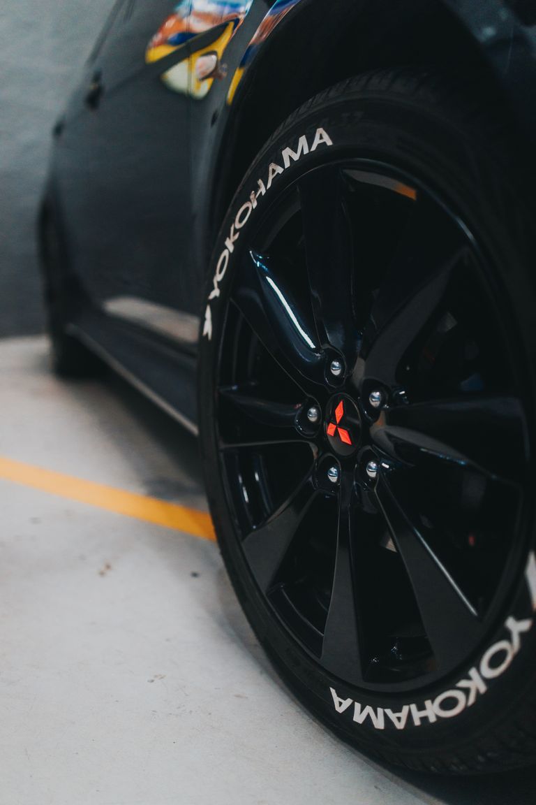 Stylish black car with custom Yokohama tires and sleek rims in a parking garage.